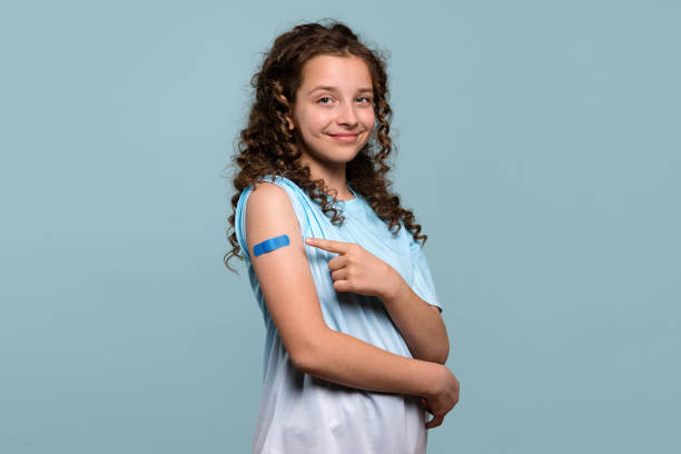 istock Smiling girl pointing at bandage on vaccinated arm. 2180399124