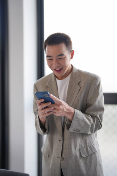 istock asian business man holding Smartphone working mobile devices. cell telephone technology e-commerce smartphone for business 2180402319