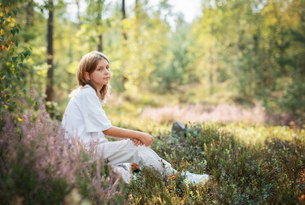 istock A young child sitting quietly in a serene forest, surrounded by vibrant greenery during a sunny afternoon 2180405412
