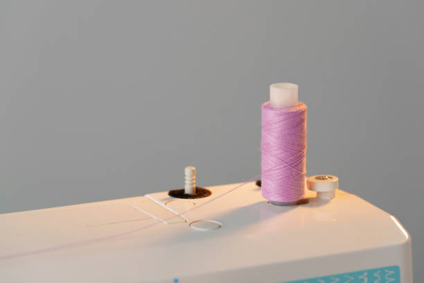A detailed close-up of a sewing machine needle threading fabric, showcasing the precision and skill involved in the sewing process. The image focuses on the machine’s foot and the material being stitched.