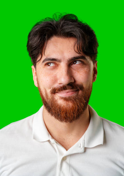 istock A smiling young man with a beard poses against a bright green background 2180414158