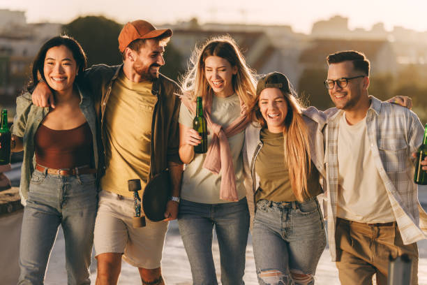 Young happy friends talking while walking embraced in the park.