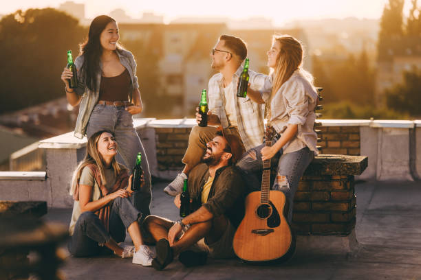 istock Cheerful friends drinking beer on a rooftop at sunset. 2180414764