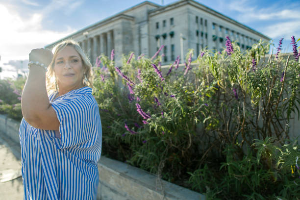 istock A confident plus size female poses with a strong fist under a bright sky 2180414856