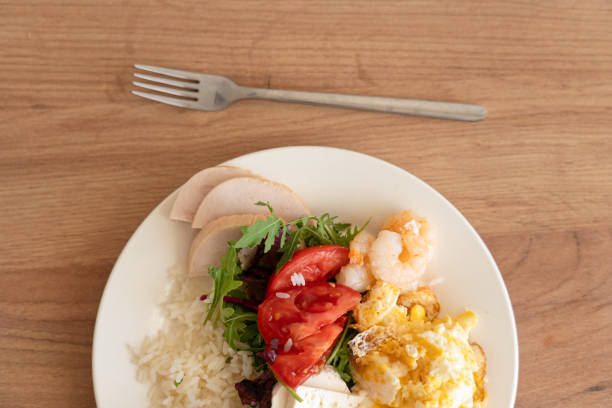 istock balanced nutrition. Scrambled eggs with shrimp and fresh vegetables served on a plate at a rustic wooden table during lunchtime 2180415951