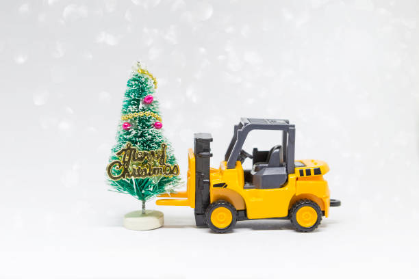 istock Yellow forklift truck with Christmas tree over blurred white bokeh background 2180419763
