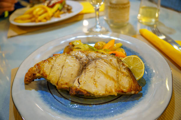 istock Mediterranean cuisine: swordfish fillet with mixed vegetables and lemon on a blue and white plate. Close-up 2180420764