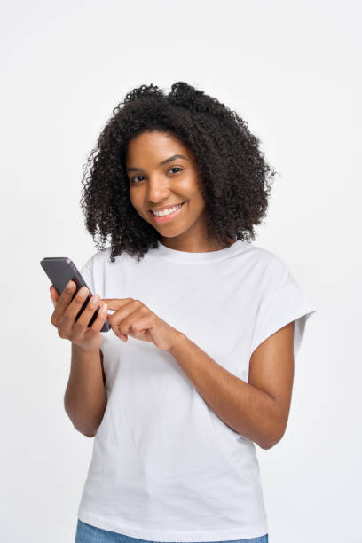 istock Young happy African girl standing isolated on white background using cellphone. 2180423082