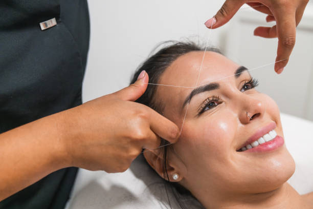 istock Beautician performing threading hair removal on forehead of client 2180429805