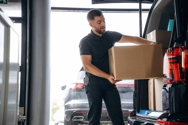istock Delivery man or loader is near the car with a box 2180436139