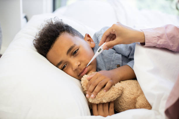 istock Young boy feeling unwell with thermometer in bed 2180439868