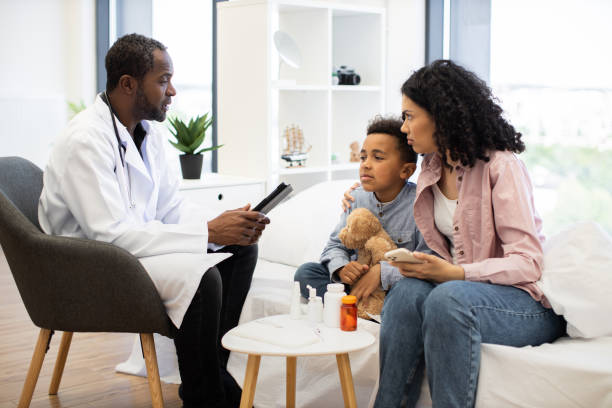 istock Doctor examining young sick African boy with caring mother present 2180439904