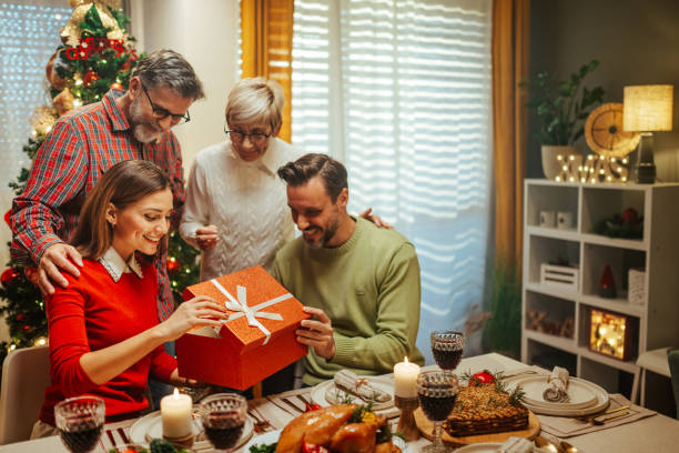 istock Family celebrating christmas opening present at dinner table 2180441596