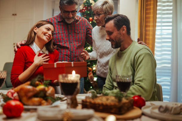 istock Family giving christmas gift at dinner table 2180441598