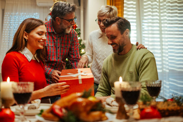 istock Happy family giving christmas present at dinner table 2180441600