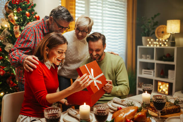 istock Happy family opening christmas present at dinner table 2180441603