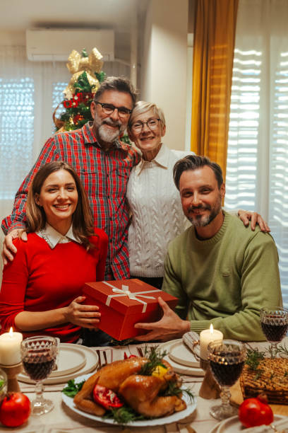 istock Happy family exchanging christmas gift at dinner table 2180441616