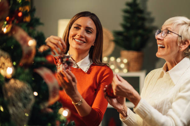 Two happy women decorating christmas tree at home