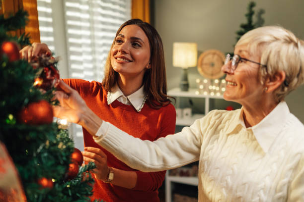 istock Smiling women decorating christmas tree at home 2180441704