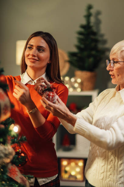 istock Women decorating christmas tree with ornaments at home 2180441707
