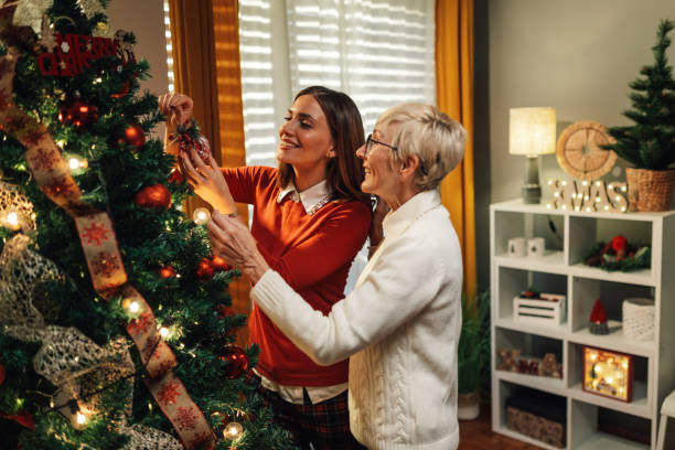 istock Women decorating christmas tree with ornaments at home 2180441727