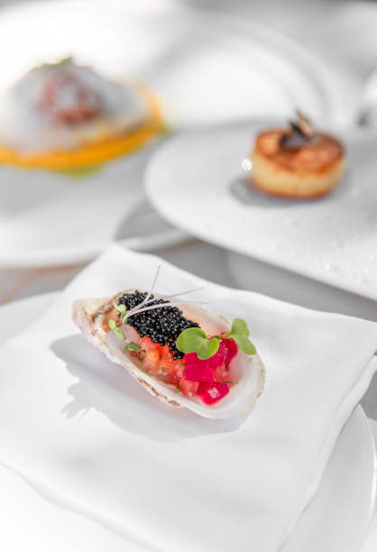 istock Michelin Fine dining restaurant Appetizers tasting menu at elegant gourmet table plates with puff pastries, caviar oyster, herb leaves and flavour gels 2180442406
