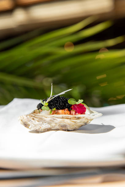 Michelin Fine dining restaurant Appetizer tasting menu at elegant gourmet table plate with caviar oyster and palm leaf