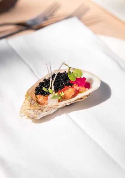 Image of a fresh oyster inside the shell with tapioca pearls and fresh baby beet greens isolated on white background