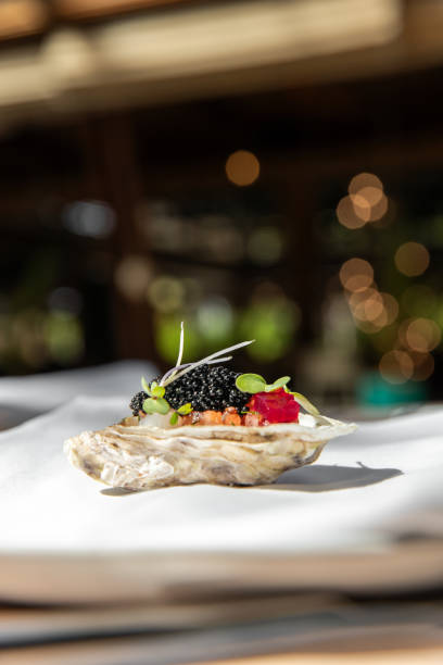 istock Michelin Fine dining restaurant oyster Appetizer tasting menu at elegant gourmet table plate with caviar and palm leaf 2180443167