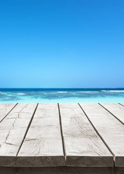 Empty wooden table top with beautiful turquoise sea and sunny blue sky background
