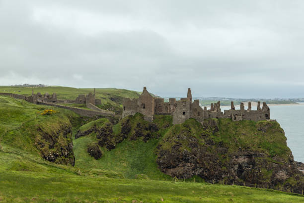 istock Dunluce Castle ruins atop grassy cliff with ocean view surrounded by green pastures cloudy sky 2180444270