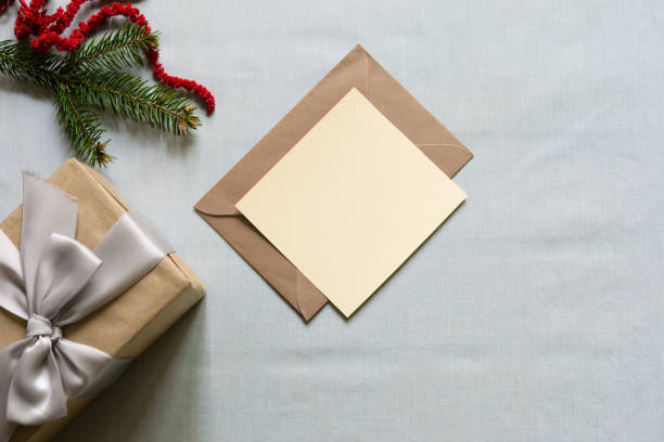 istock Empty blank christmas card mockup on envelope with gift box and fir tree branch on light plain background. christmas greeting card. 2180446943