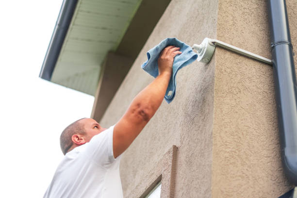 istock Electrician cleaning outdoor wall sconce with rag 2180447150