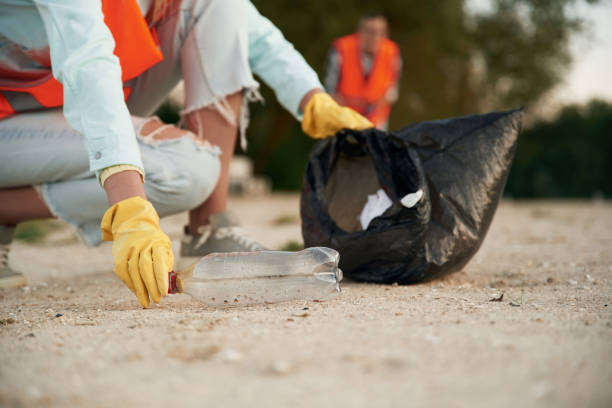 istock Picking up the bottle. A volunteers collects garbage on a muddy beach 2180450295