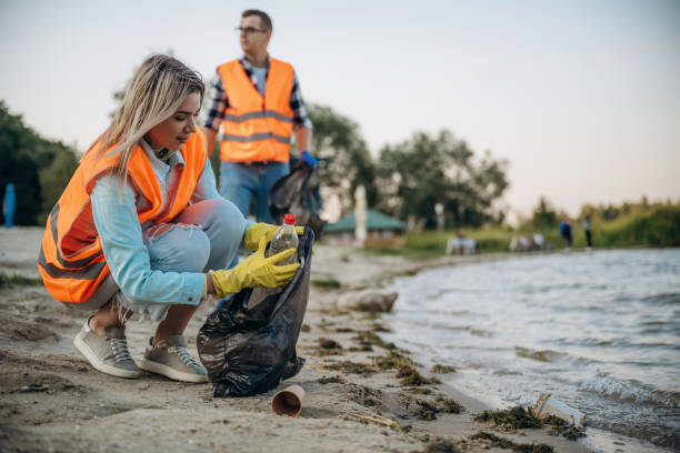istock On the shore. A volunteers collects garbage on a muddy beach 2180450455