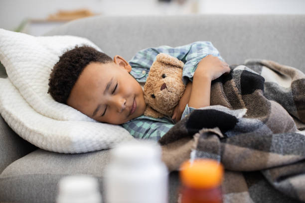 istock Young boy resting on sofa with teddy bear for comfort 2180458365