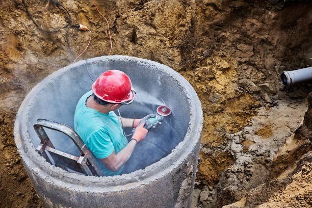 istock Cutting hole for sewer pipe in concrete septic tank ring using diamond wheel on an angle grinder. 2180459478