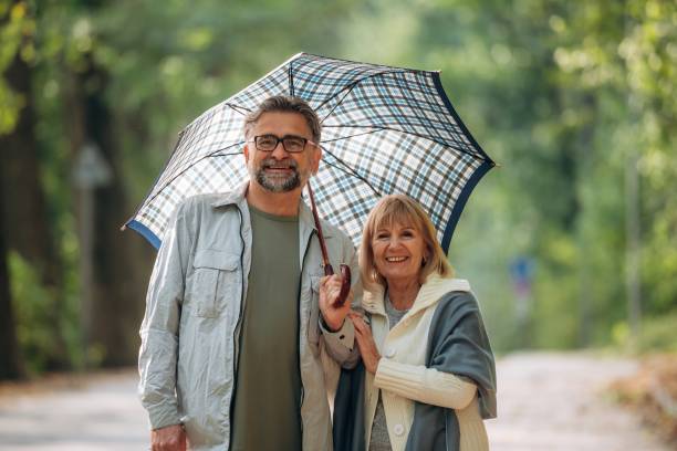 istock Under the umbrella. Senior couple together outdoors at nature 2180465973