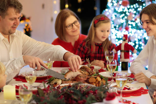 istock Family with kids having Christmas dinner at tree 2180466702