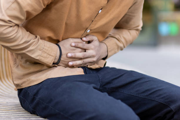 istock Man experiencing stomach pain while sitting, indicating discomfort and health issues related to gastrointestinal discomfort or upset 2180470696