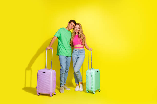 istock Full body portrait of two nice young partners cuddle suitcase empty space isolated on vibrant yellow color background 2180473090