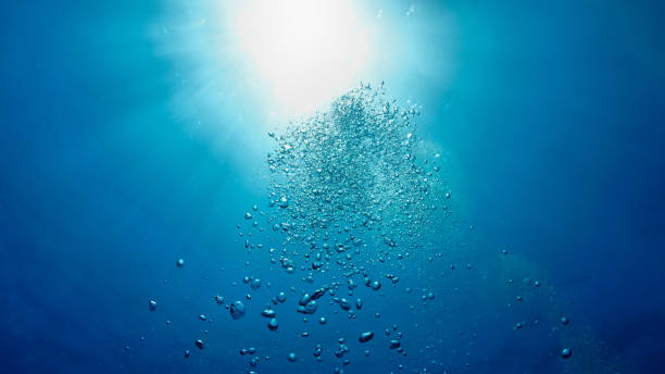 istock Rays of light and air bubbles below the blue ocean surface 2180473322