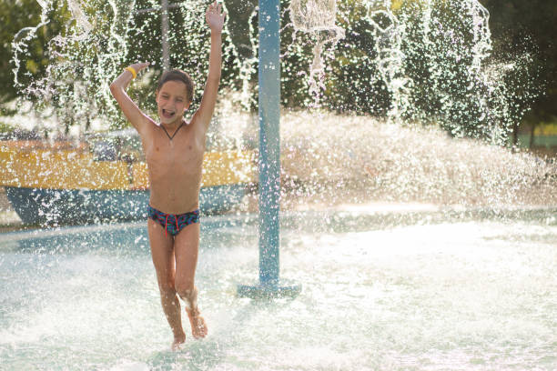 istock Boy running under waterfall in water park 2180474523