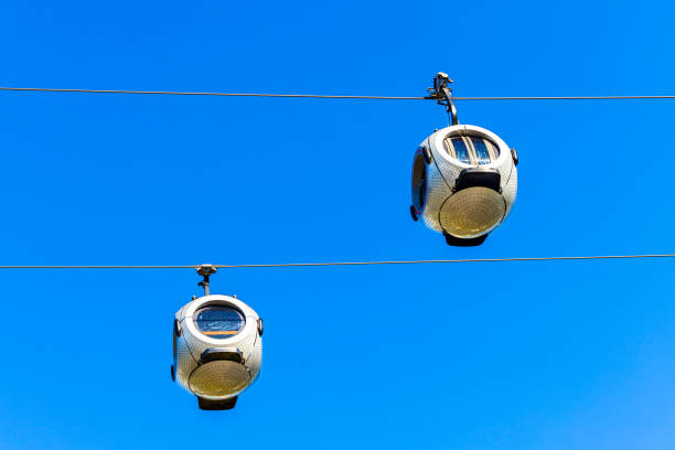 the aerial tram cabins move in reverse. a cable car with round passenger cabins. cable car against blue sky. aerial tramway. cable car operation.