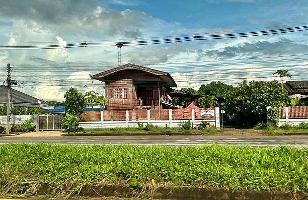 Thailand - Chiang Mai district - Architecture on the street Driving along the road around Chiang Mai, you can see this kind of architecture on the side of the road. Wooden houses and electricity poles.08/07/2024