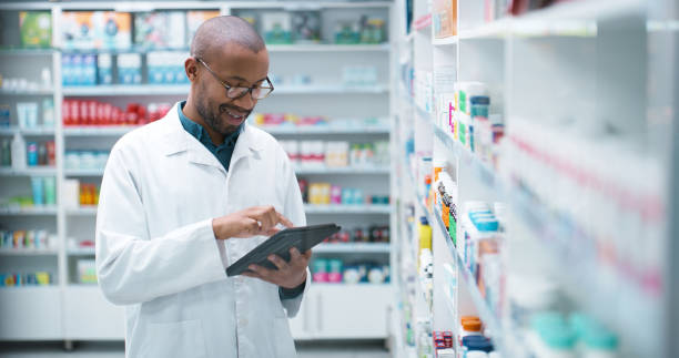 istock Black man, pharmacist and medication with tablet for pharmaceuticals, inventory or checking stock at pharmacy. Young African, male person or medical employee on technology at drug store or dispensary 2180482933