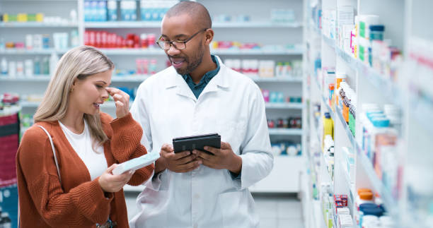 istock Man, customer and pharmacist with tablet for health advice, medication or side effects at pharmacy. Medical professional, employee and client with box or drugs for cure, remedy or help at dispensary 2180483099