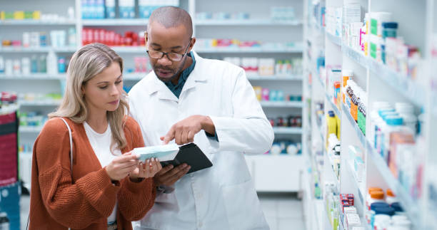 Customer, pharmacist and box with medication for advice, consultation or help at pharmacy. Medical professional, consultant and client with pharmaceuticals for symptoms or side effects at dispensary