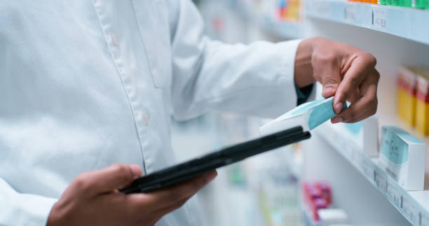 istock Hands, pharmacist or man with tablet, pills or online reading for product info. Checking label, closeup or pharmacy with professional, medical or tech with internet, connection or drug store with app 2180483165