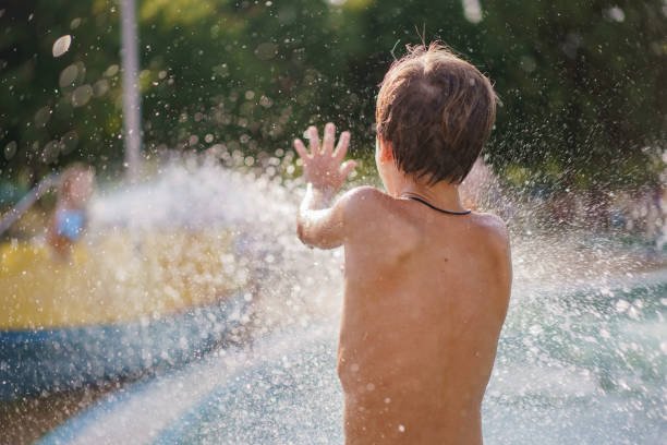 Rear view of little boy plays with water in a water park in the summer